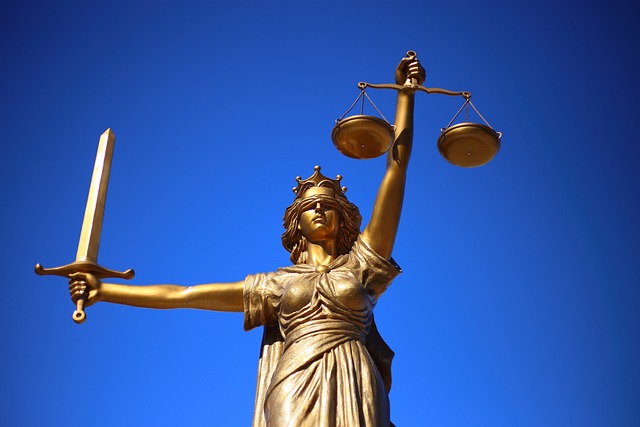 تمثال لسيدة العدالة تحت أفق أزرق غامق.
