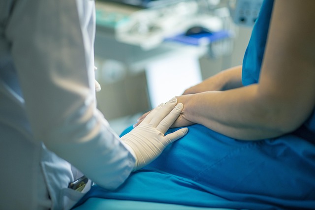 خدمات ترجمة الرعاية الصحية: كل ما تنطوي عليه 3 شخص يرتدي معطف مختبر أبيض ويضع يده التي يرتدي قفازاً أبيض على حضن شخص يرتدي رداء المستشفى الأزرق.