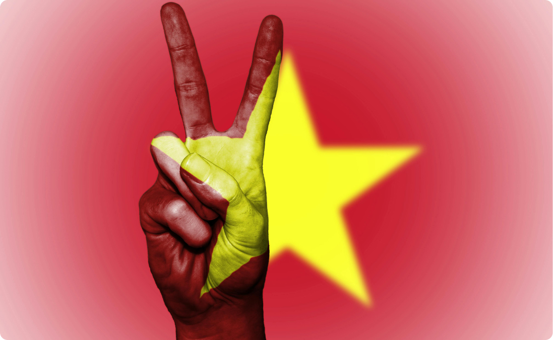 Uma mão mostrando o sinal de paz e a bandeira do Vietnã representando traduções simplificadas de idiomas.