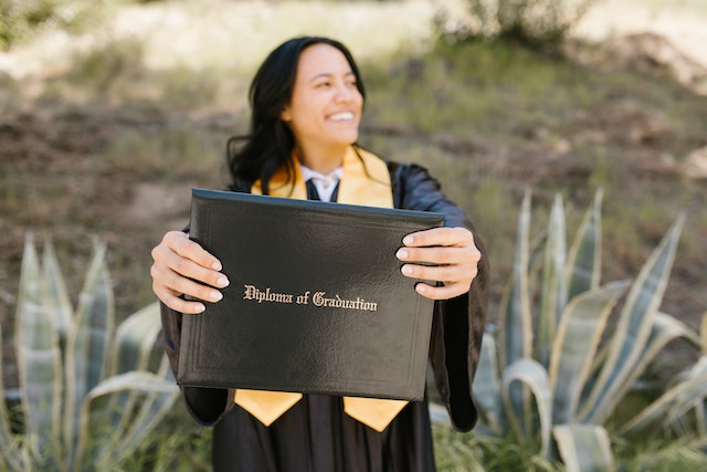 Uma mulher segurando seu diploma.
