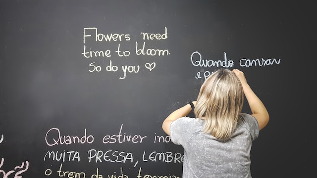 Uma foto de alguém escrevendo frases em vários idiomas em um quadro-negro.