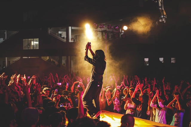 Um artista se apresenta em um palco central na frente de um público.
