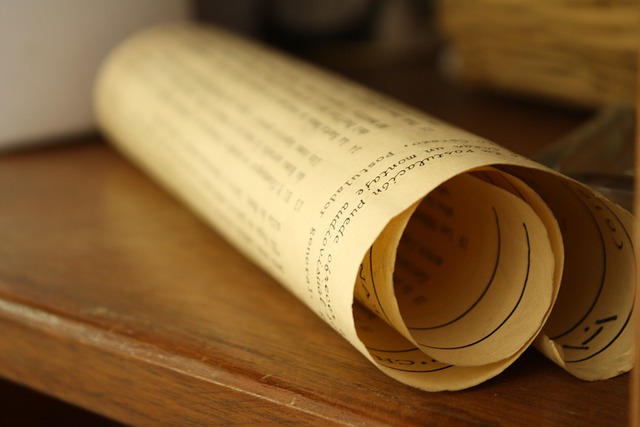 Um papel de pergaminho enrolado está em uma mesa de madeira.