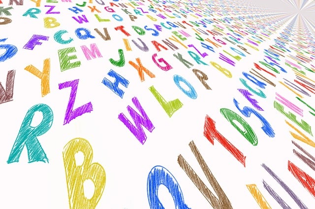 Vista em close de alfabetos coloridos espalhados em uma superfície branca.
