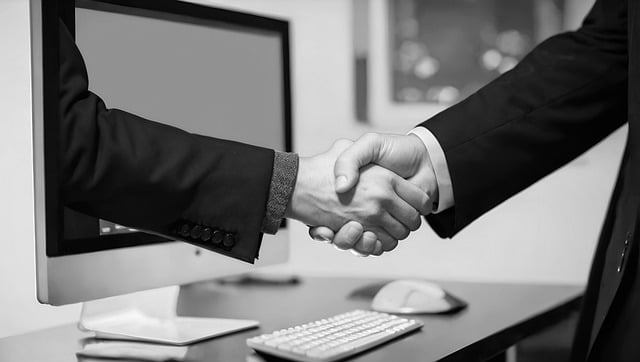 Guia de tradução de documentos para empresas globais 7 Duas pessoas vestindo ternos apertam as mãos diante de um computador.