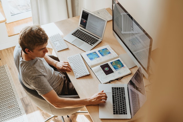 Ein Mann, der mit drei Computern eine notariell beglaubigte Übersetzung erstellt.