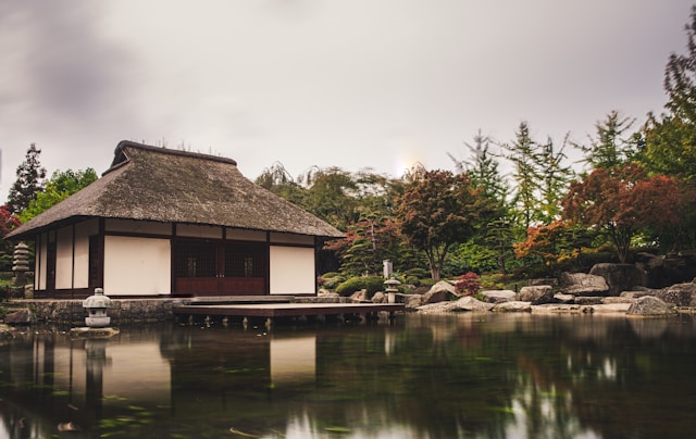 Die einfachsten Länder für den Immobilienkauf als Ausländer 5 Ein braunes japanisches Haus neben einem Gewässer, umgeben von Bäumen.