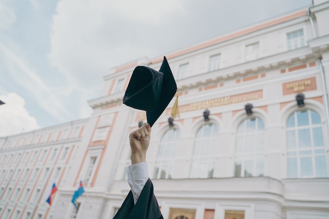 Un graduado lanzando su gorra al aire.