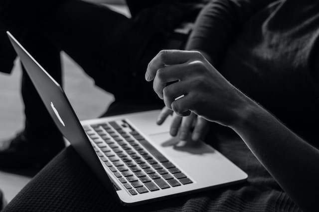 Traductor jurídico en línea: Dónde encontrar la mejor opción 3 Fotografía en blanco y negro de alguien utilizando su MacBook para buscar servicios de traducción jurídica.