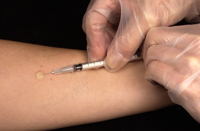 Traducción de vacunas: Su guía de vacunación perfecta 5 Una mano con guantes transparentes inyecta en el brazo de alguien.