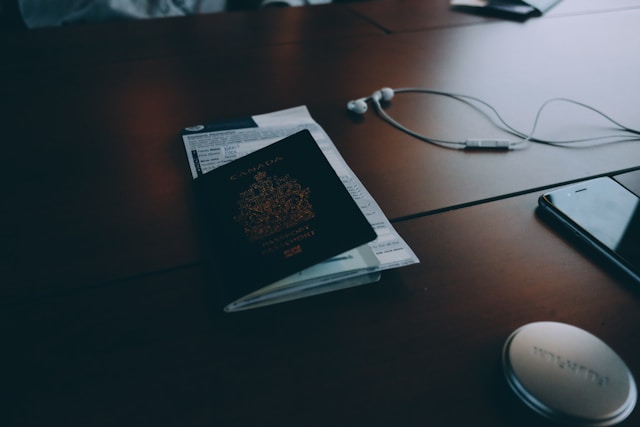Agencia de traducción en Canadá: Las 5 mejores para usted 5 Un pasaporte canadiense sobre una mesa junto a un teléfono y un par de auriculares con cable.