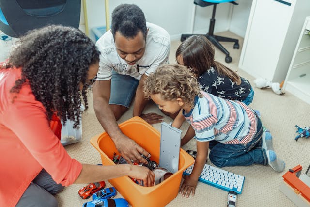 ¿Cuál es el país más fácil para adoptar? 5 Dos padres adoptivos juegan con coches de juguete junto a sus hijos en su dormitorio.