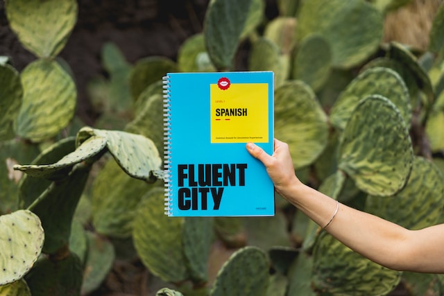 Une photo d'une personne avec un livre de niveau 1 de Fluent City pour l'espagnol.