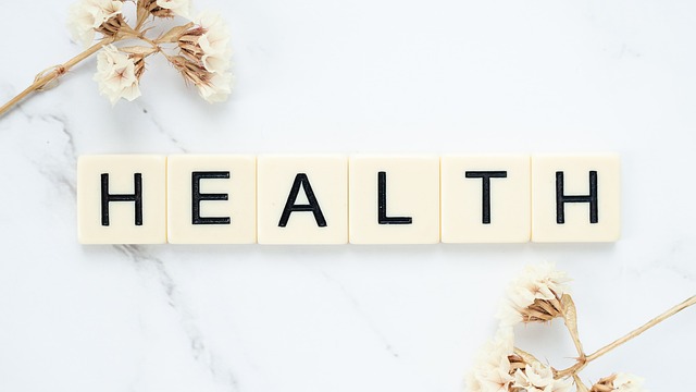 Services de traduction dans le domaine de la santé : Tout ce qu'ils impliquent 4 Des carreaux de marbre blancs carrés écrivent "Health" à côté de fleurs blanches sur une surface blanche.