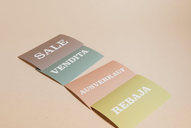 Services de traduction multilingue : Pourquoi sont-ils importants ? 5 Plusieurs feuilles de papier avec le mot "Sale" dans différentes langues.