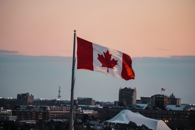 Services de traduction IRCC : Trouvez l'agence qui vous convient le mieux 3 Un drapeau canadien flotte dans le ciel avec un magnifique coucher de soleil en arrière-plan.