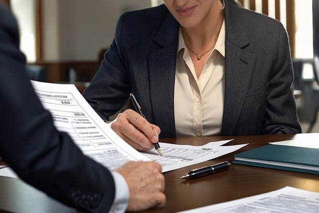 Services de traduction juridique : Comment choisir les bons prestataires 6 Une personne en costume noir rédige un document en étant assise en face d'une autre personne.