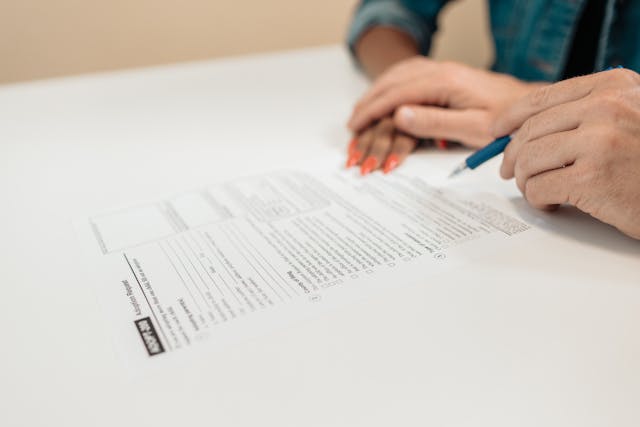 Adoption nationale ou internationale : Comment cela fonctionne-t-il 3 Une personne signe un formulaire de demande d'adoption.