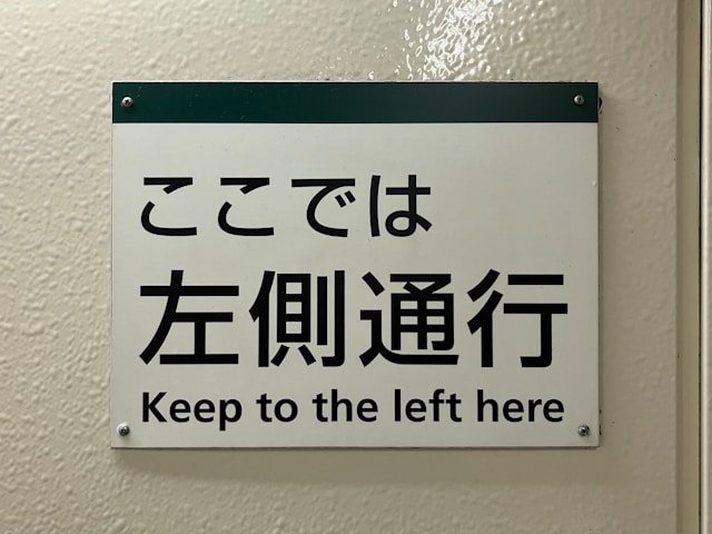 Qu'est-ce que la traduction et la localisation ? 5 Gros plan d'un panneau sur un mur blanc en trois langues.