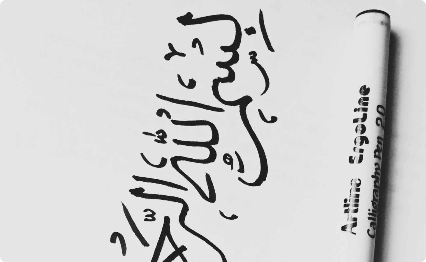 Black Arabic script on a white surface next to a capped white pen representing Arabic translation services.