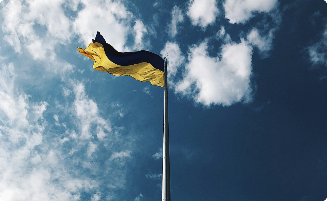 A Ukrainian flag on a flagpole with the sky in the background representing real life examples of Ukrainian translations.