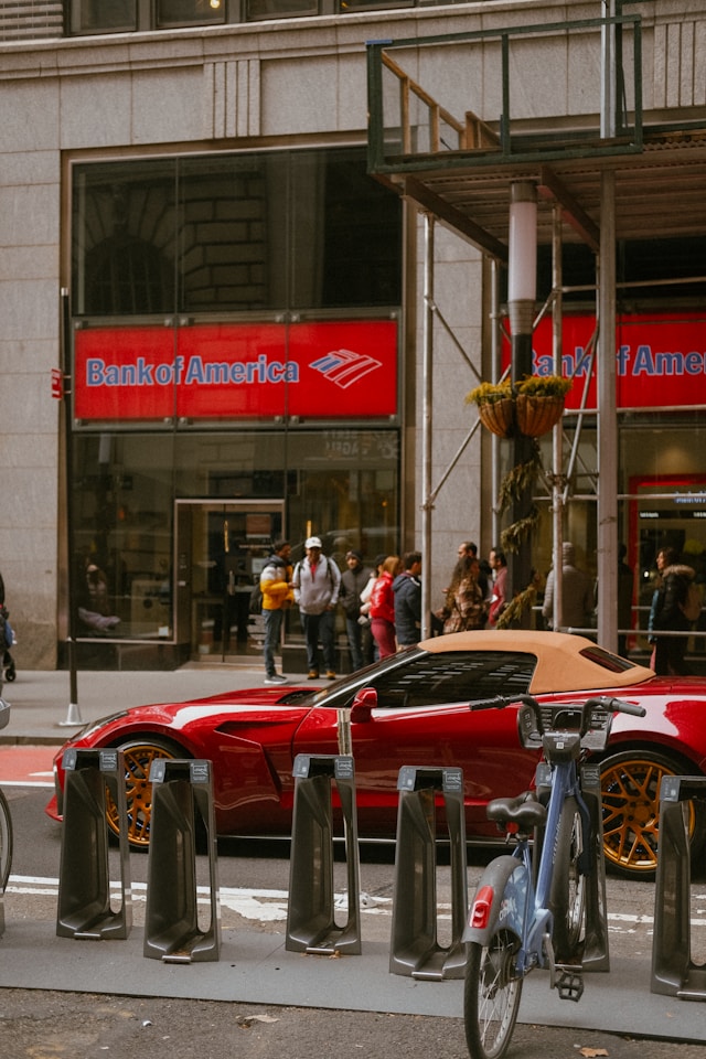 Uno straniero può aprire un conto bancario negli Stati Uniti? 6 Un'auto sportiva rossa accanto a un edificio della Bank of America.
