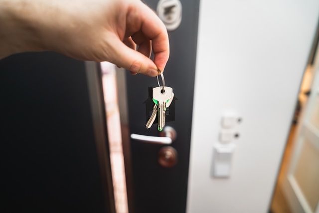 I Paesi più facili per acquistare una proprietà come straniero 4 Una persona tiene in mano diverse chiavi con un portachiavi nero davanti a una porta.