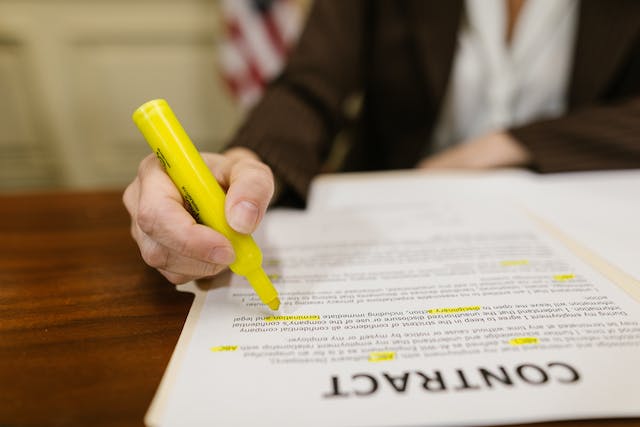 Certyfikowane usługi tłumaczeń prawniczych: Najlepsi dostawcy do wyboru 5 Obraz osoby podkreślającej niektóre części umowy prawnej żółtym atramentem.