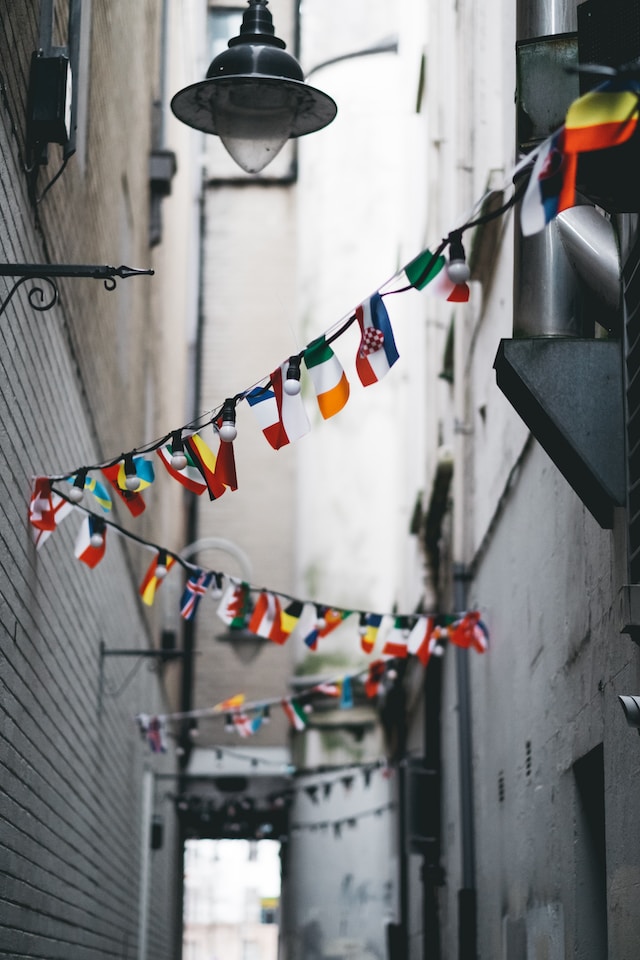 A string of small flags from many different countries hanging over a street. 