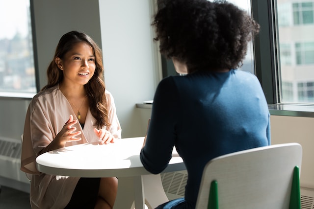 Two businesswomen discuss using a certified translation service. 