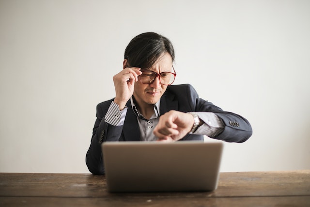 A confused businessman checking the time on his wristwatch.