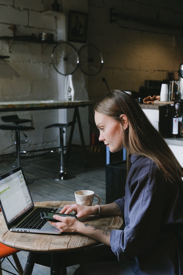 A young businesswoman using a laptop in a cafe to translate documents.