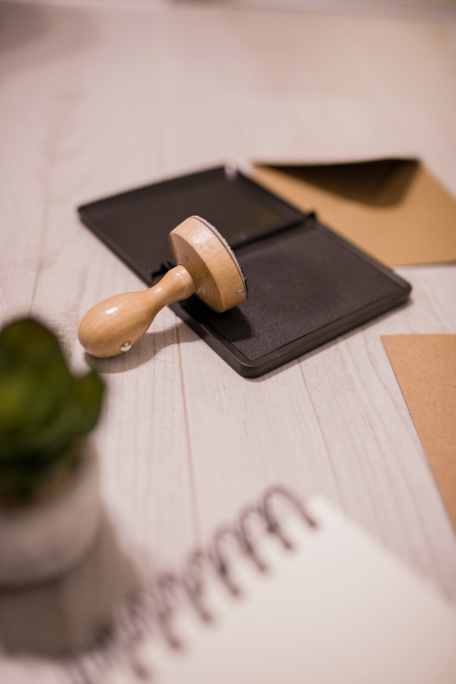 An inkpad and a stamp on a table next to translated document.