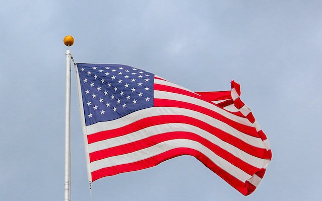 USA flag waving on a white metal pole.