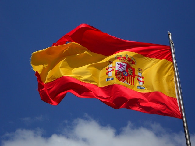 A Spanish flag waving on a flagpole. 