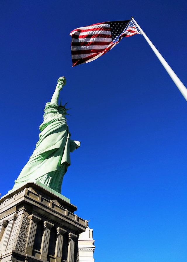 The Statue of Liberty next to the US flag.