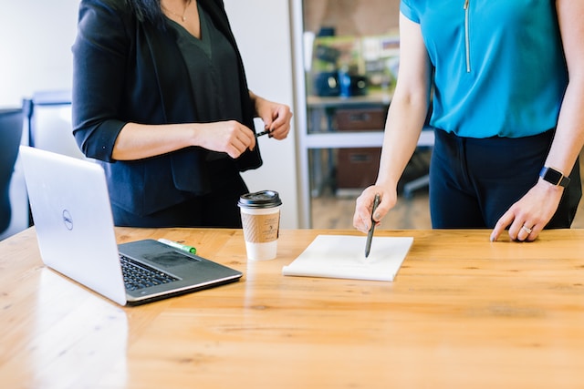 A photo of someone pointing to a piece of paper on a desk.