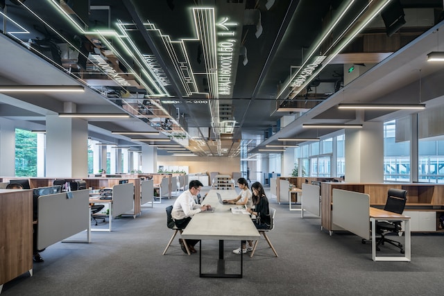 A picture of several people sitting on a table in an office space.
