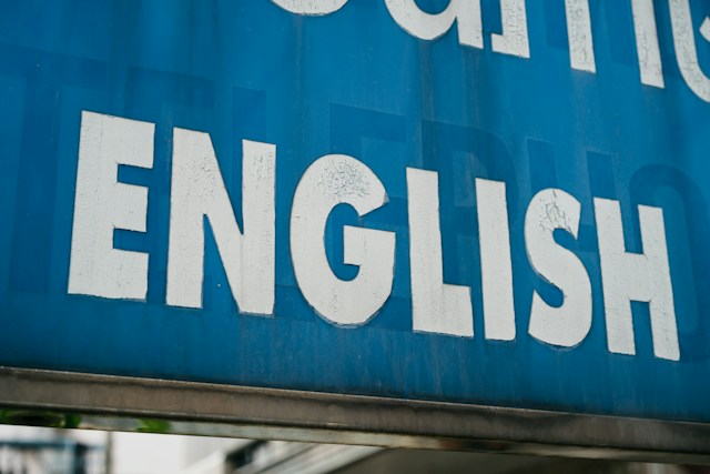 A picture of a blue sign with the wording “English” in white paint.