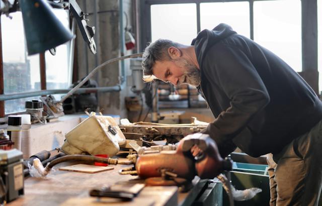 A photo of a person fixing items on a table in a garage.