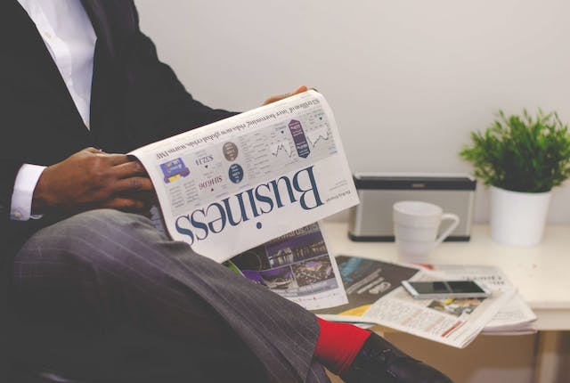 A picture of a person reading a business newspaper.