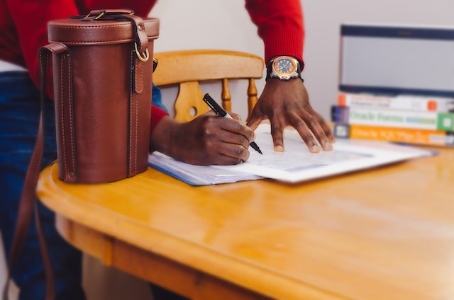 A picture of a person signing a document on a desk.