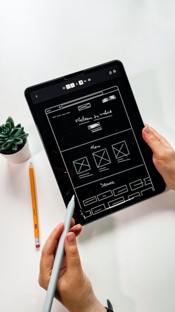 A person holds a black iPad. They appear to be working on the development of a product’s information architecture. 
