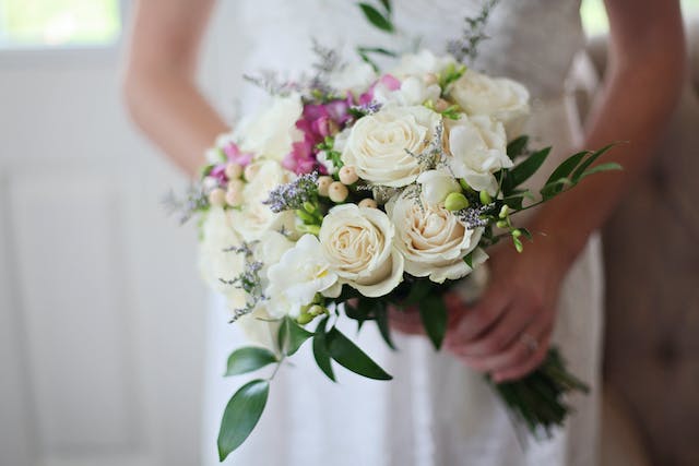 A picture of a bride holding a white bouquet.