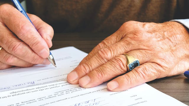 A photo of someone with a ring signing a document.