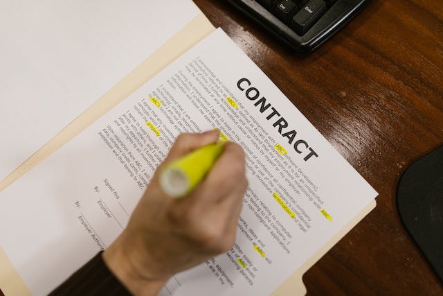 A picture of someone highlighting parts of a printed contract.