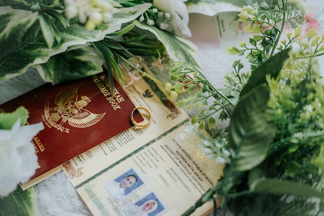A picture of marriage documents, a ring, and bouquets on a table.