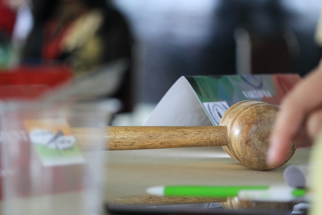 A photo of a wooden gavel and some papers on a desk.
