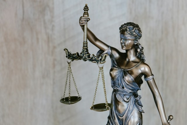 Close up of a bronze statue of Lady Justice holding scales while blindfolded.