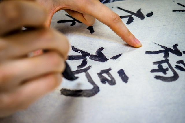 A closeup photo of a person writing in Chinese with black ink. 